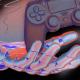 A stylized digital illustration of a hand wearing a futuristic SIMA glove, manipulating a ghostly image of a game controller against a dark, gradient background.