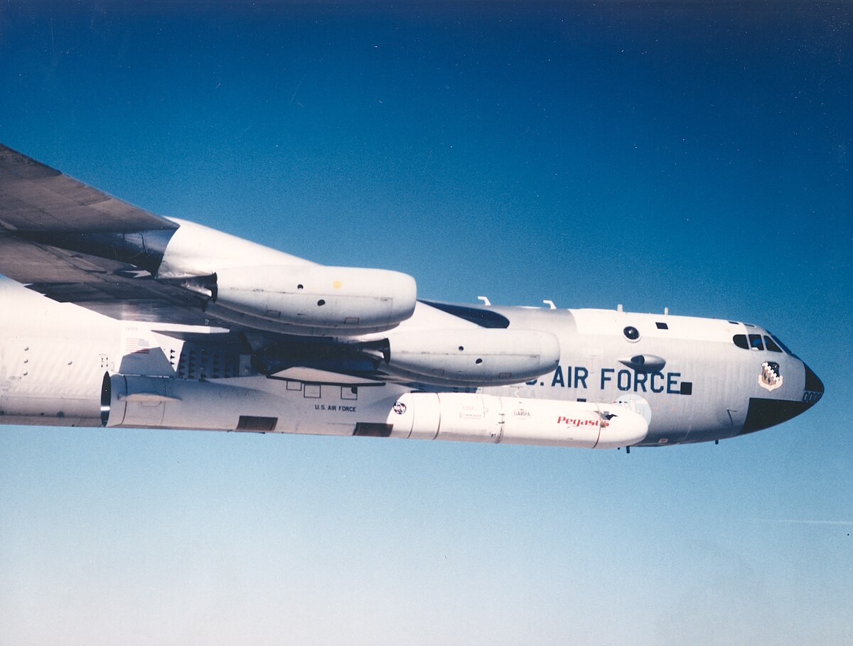 A U.S. Air Force aircraft in flight against a clear blue sky, with a large wing and visible engine.