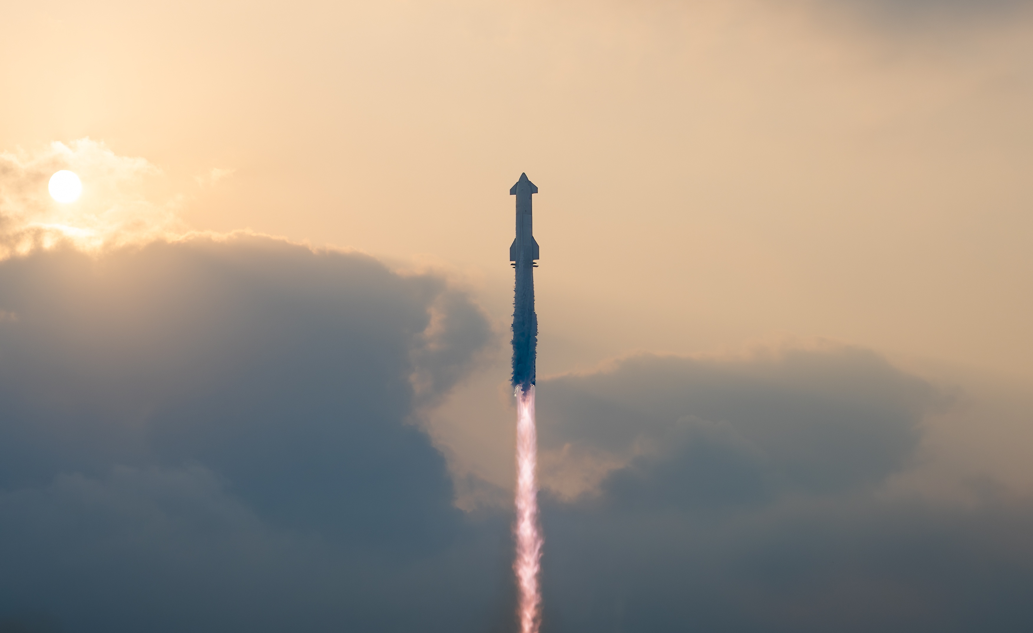 Rocket launching into a cloudy sky with the sun partially visible.