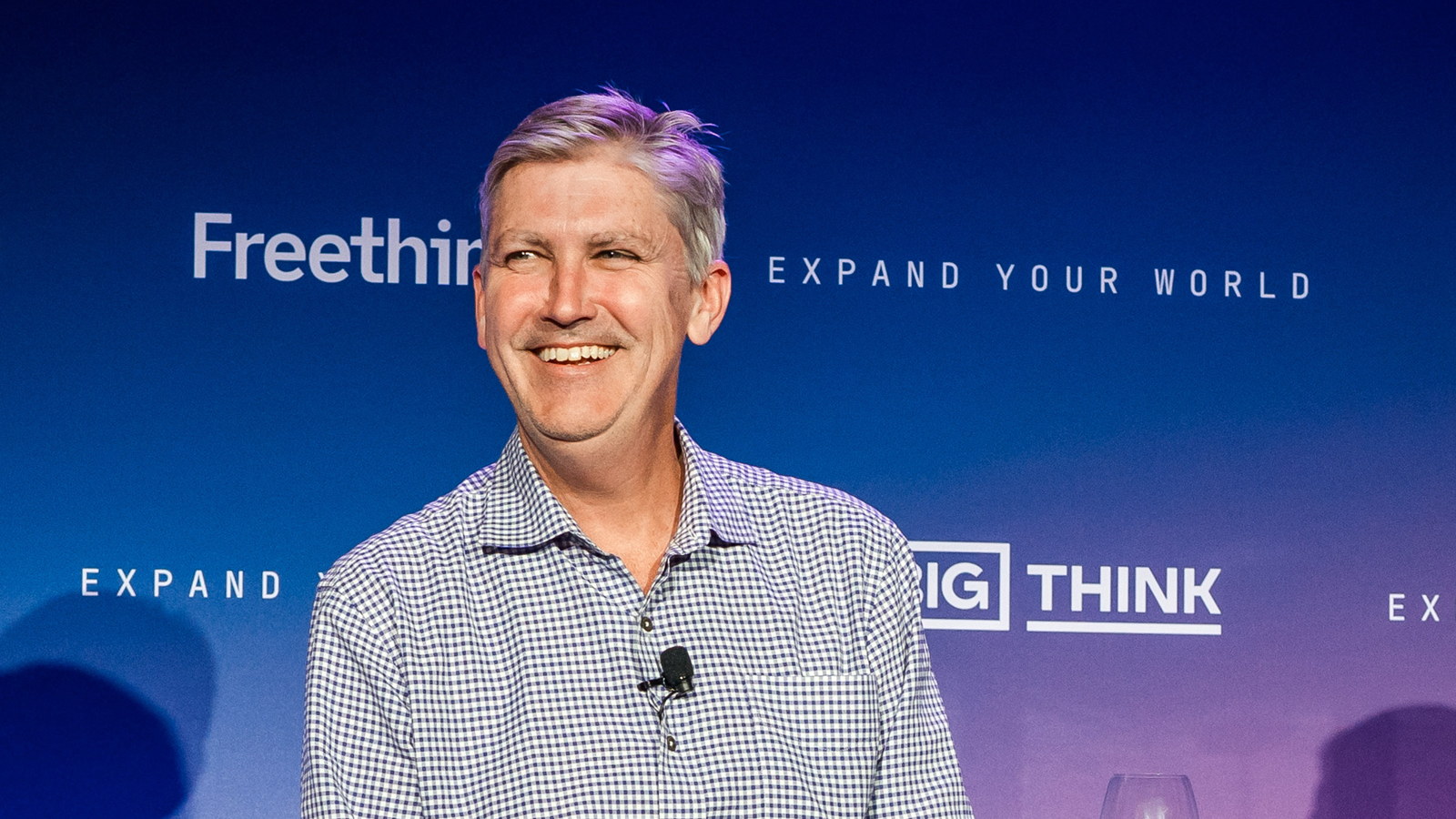 A man with gray hair and a mustache sits smiling in front of a blue background with "Freethink" and "Big Think" logos.